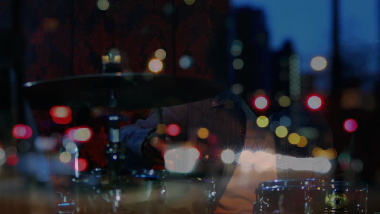 Window reflection resolving and revealing drummer striking kit with city bokeh overlaying for music