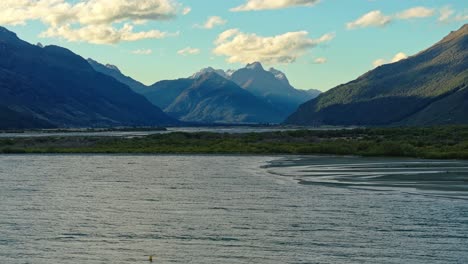 Luftaufnahme-über-Die-Oberfläche-Des-Lake-Wakatipu-Mit-Sonnenstrahlen,-Die-über-Die-Berge-Strahlen