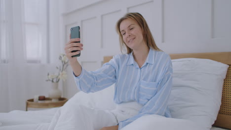 Businesswoman-having-a-video-call-in-hotel.-Happy-girl-lies-on-the-bed-talks-with-friends-via-video-call.