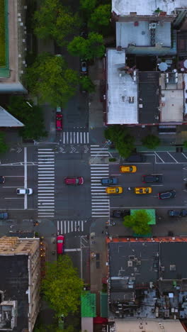 lots of yellow taxi cabs moving among other transport by the streets of new york. buildings tops from aerial view. vertical video