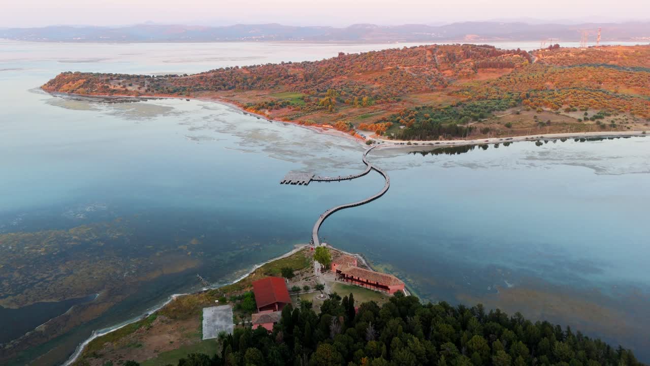 A wooden pier stretching across a lagoon in albania at sunset , aerial view