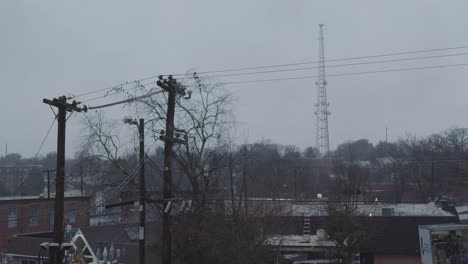 A-wide-shot-of-a-rainy-day-overlooking-a-sleepy,-blue-collar-town-with-a-tall-cellphone-tower-looming-in-the-background