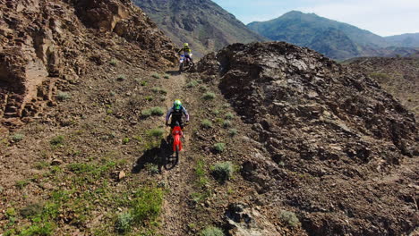 dirt bike riders riding down mountain slopes in the uae