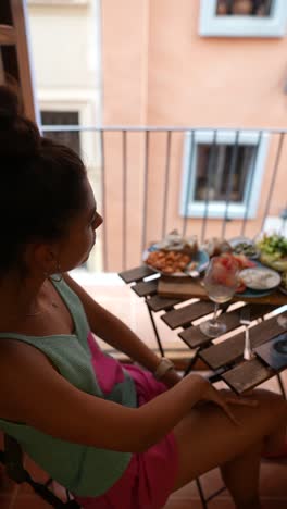 woman enjoying a meal on a balcony with city view