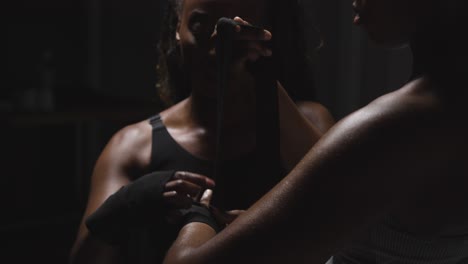 studio shot of women putting on boxing wraps on hands before exercising together 2