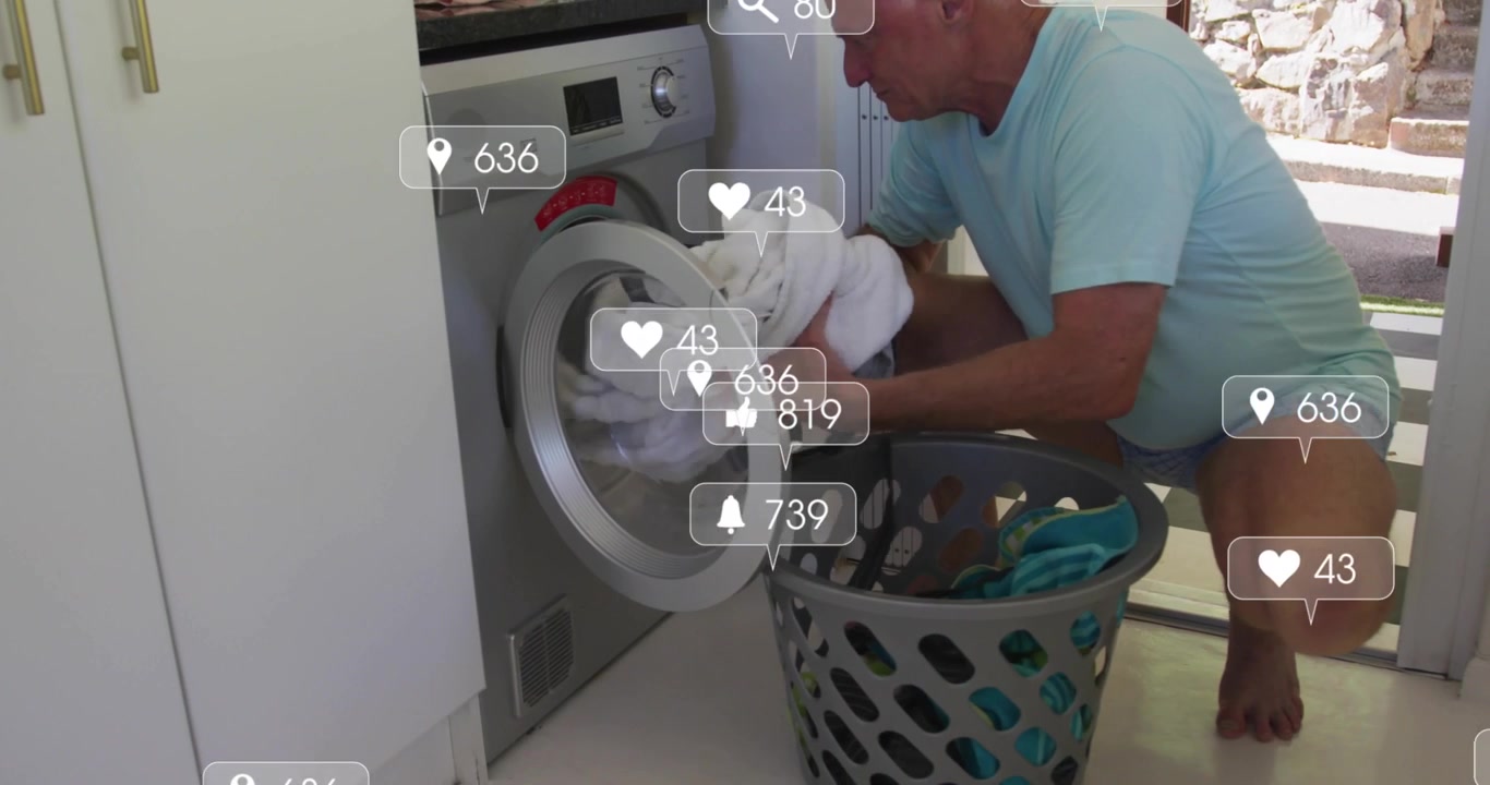 Senior man entering laundry room and loading towels into washer for washing with social media icons