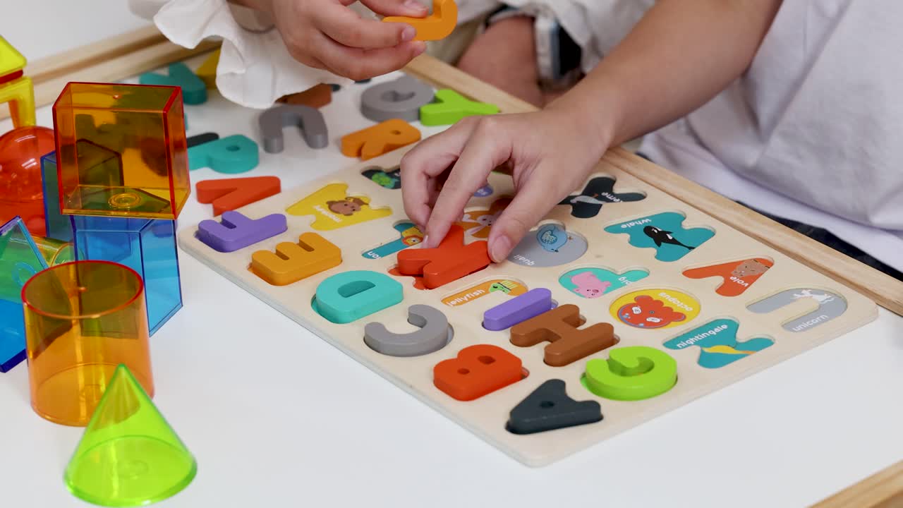 Two children arrange colorful alphabet puzzle pieces on a table in bright, natural lighting