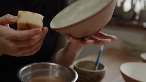 preparing for the kiln, smoothing a ceramic bowl, close up view.