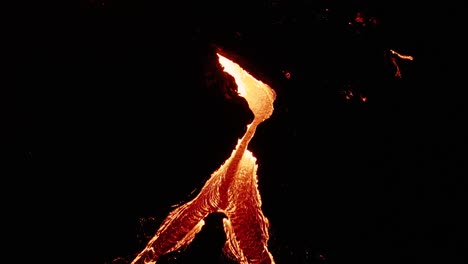 lava river splits into two streams at night, surrounded by basalt rock, aerial