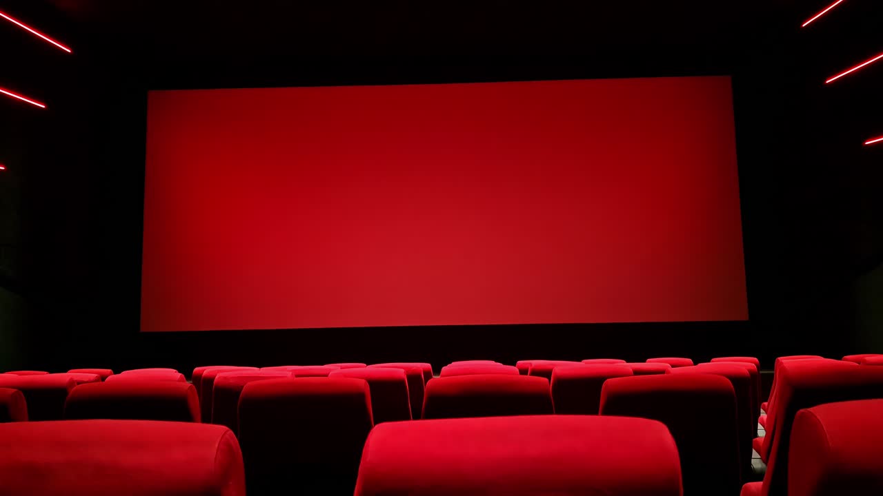 Interni di un cinema moderno vuoto con poltrone rosse e schermo bianco in un ambiente scuro