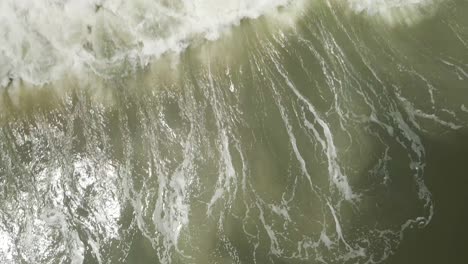 las olas se rompen dramáticamente sobre la costa de la playa de arriba hacia abajo aérea
