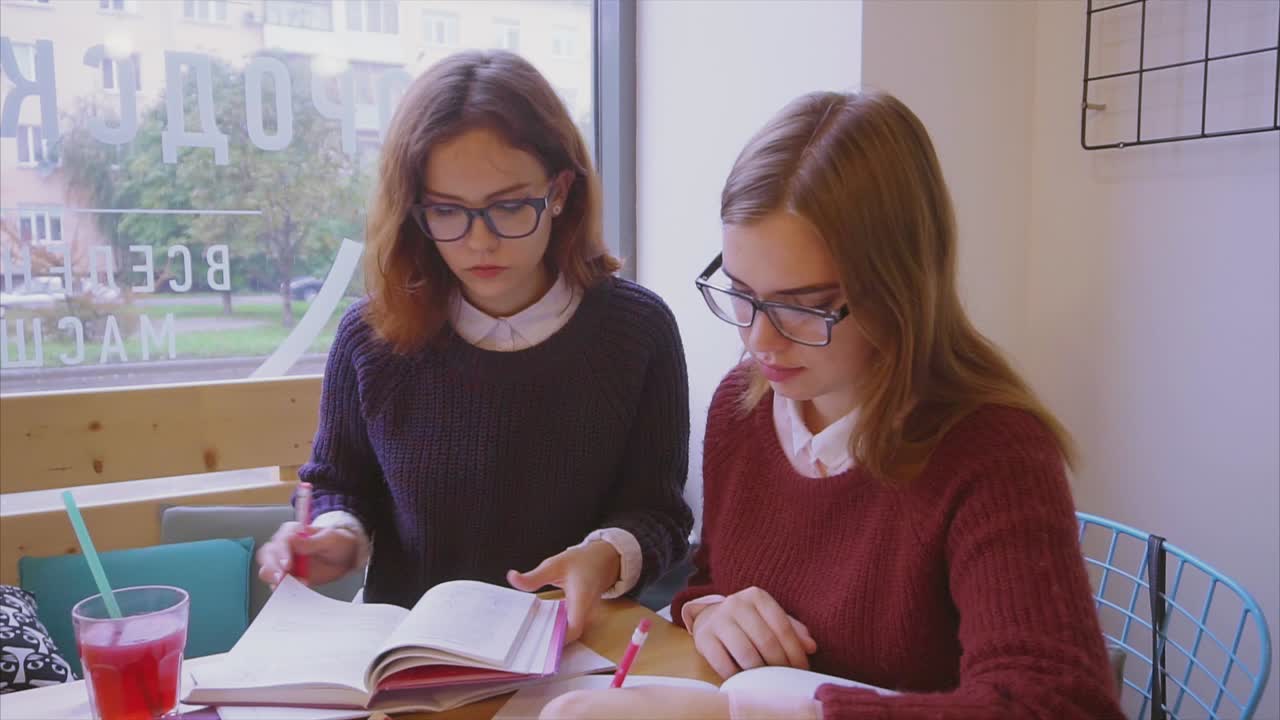 dos chicas estudiando en un café
