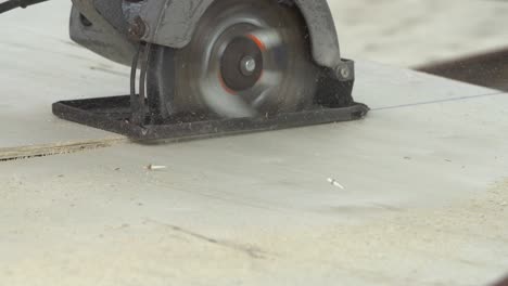 construction worker cutting wood planks with circular electric saw outdoors