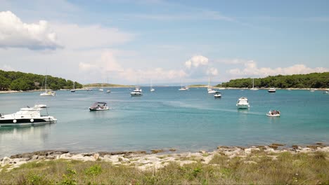 Boats-moored-in-the-clear-blue-water-at-Beach-Njive,-Premantura,-Croatia