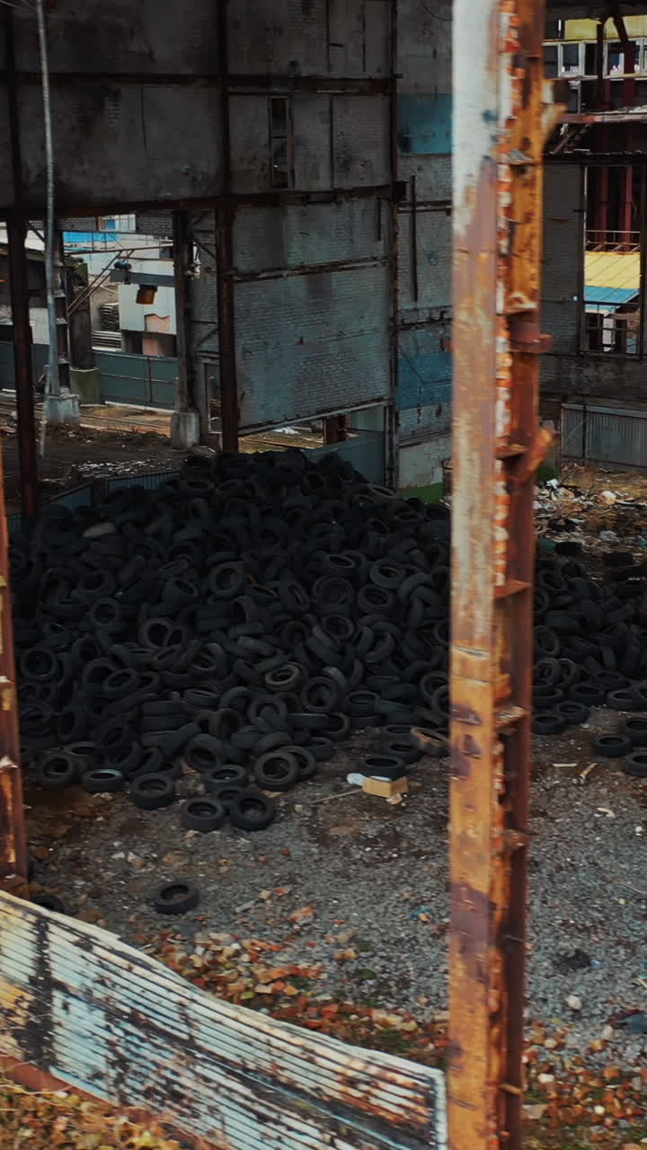 Old used tires in abandoned factory. Aerial view of an abandoned industrial plant Vertical video