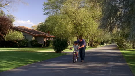 father teaching son to ride a bicycle
