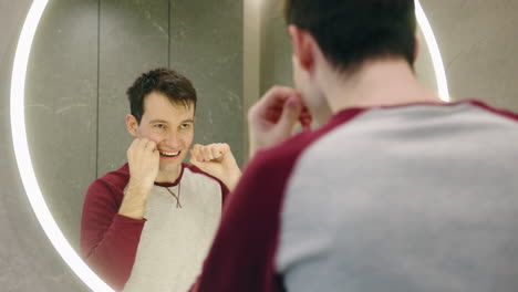 man flossing in bathroom mirror