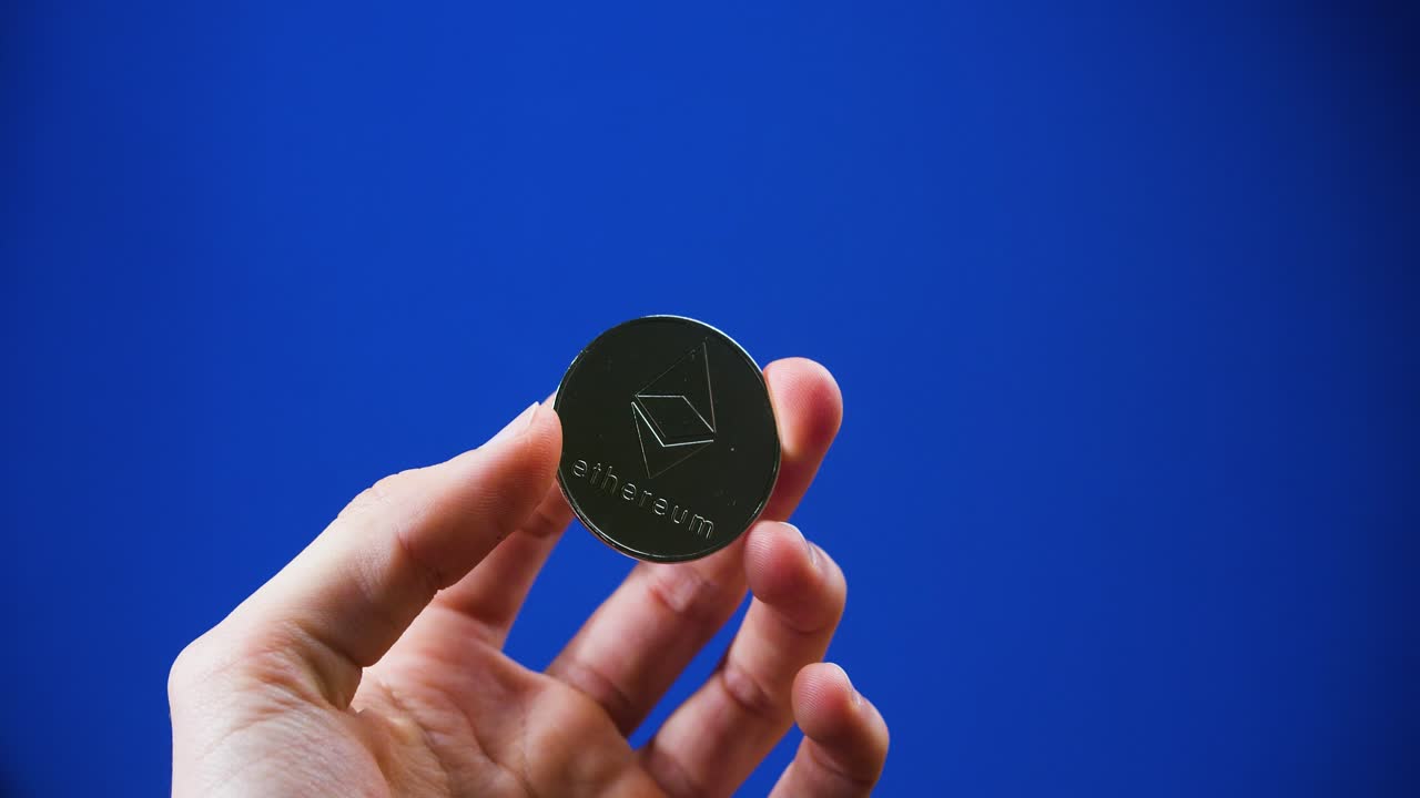 Hands holding fake Ethereum crypto coin in blue background. Close up