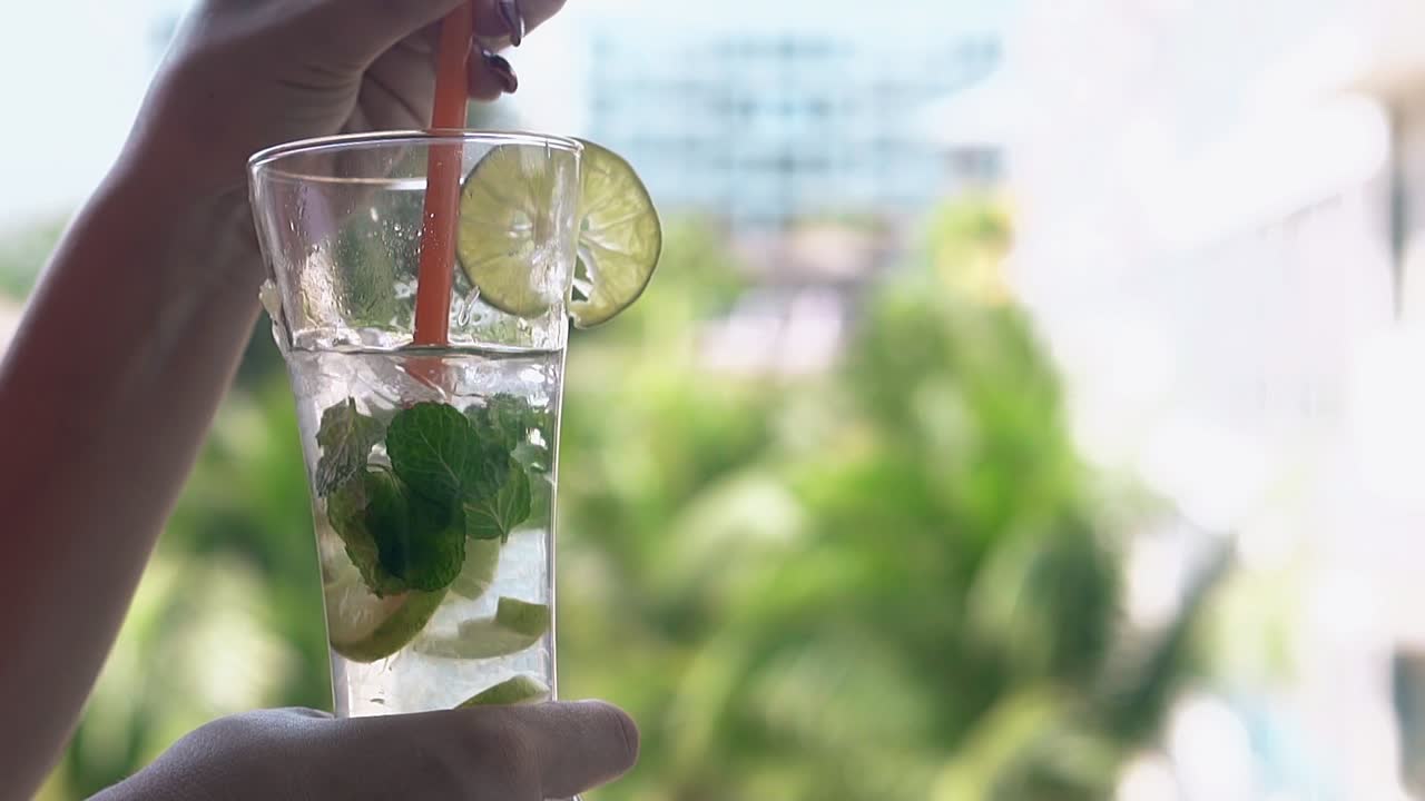 여자 손이 높은 유리잔에 얼어붙은 모지토  ⁇ 테일을  ⁇ 는다