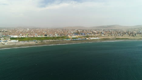 Estableciendo-Una-Toma-De-Drones-Acercándose-Al-Paisaje-Urbano-Del-Soleado-Huacho,-En-El-Brumoso-Perú