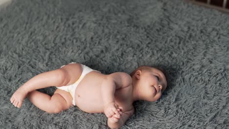 top view of baby girl lying on her back trying to roll over