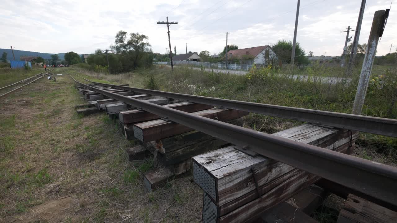 A new section of railroad track being built. Steel rails on stacked wooden sleepers showcase a transport infrastructure project, symbolizing progress and development in the countryside
