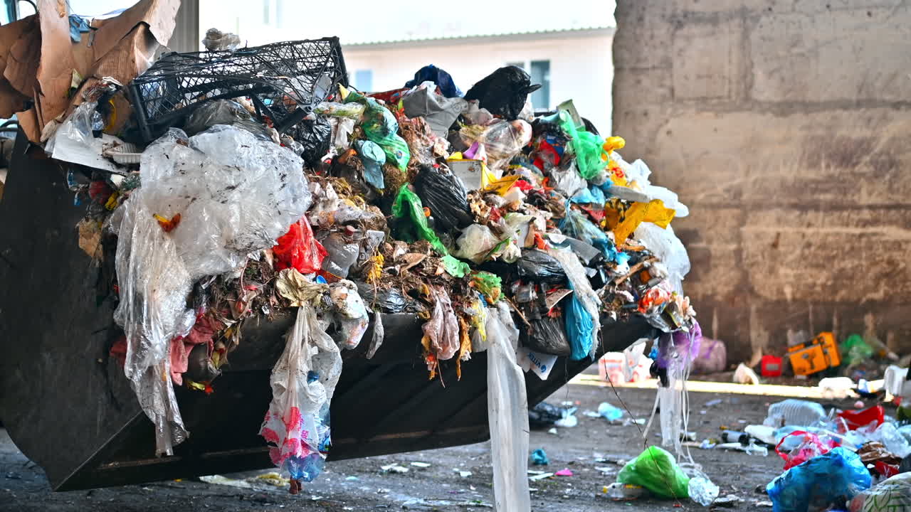 An excavator carries garbage at waste sorting plant. Slow motion