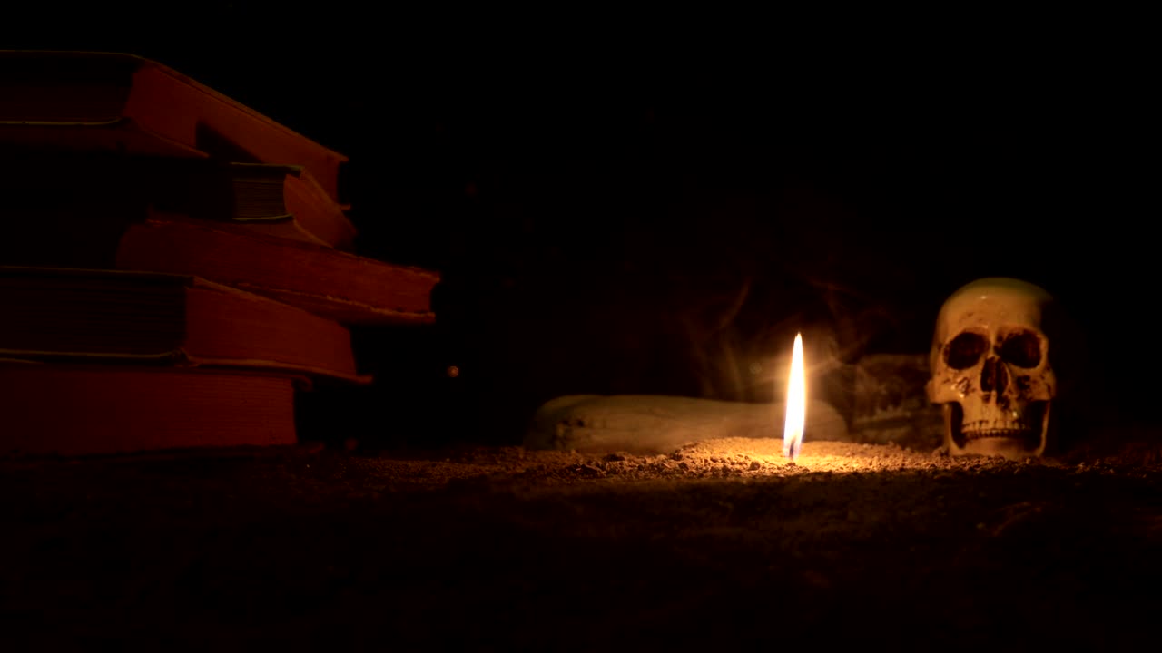 마법사의 책상: 불로 비추는 책상, 인간의 두개골, 모래 표면에 오래된 책, 어두운 톤의 안개 배경에 다른 요소를 가진 할로윈 정물 배경, 슬라이더