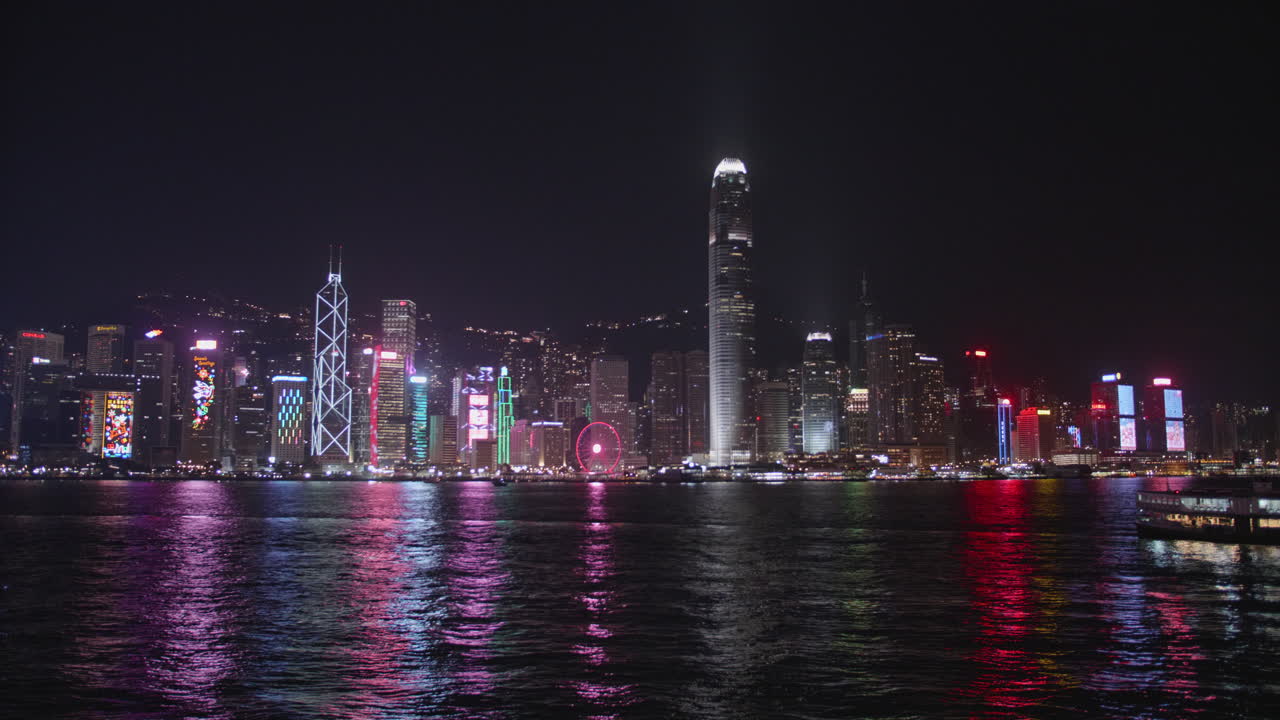 Victoria Harbour by night, Hong Kong, China. Beautiful high dynamic range professional footage. Central skyscrapers in the background a the Star Ferry passing by.