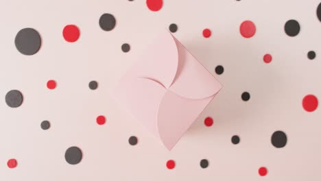 overhead view of pink gift box on white background with red and black dots