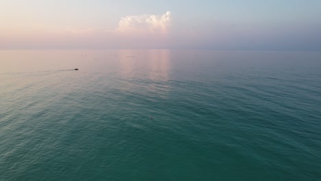 Pan-out-aerial-view-of-a-kayak-on-the-Gulf-of-Mexico-at-sunrise-on-Pensacola-Florida-Beach-with-Fluffy-clouds-at-sunrise