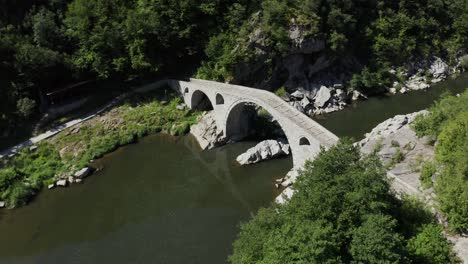 approaching drone shot moving overhead of the devil's bridge and the arda river, located in the town of ardino at the foot of rhodope mountains in bulgaria