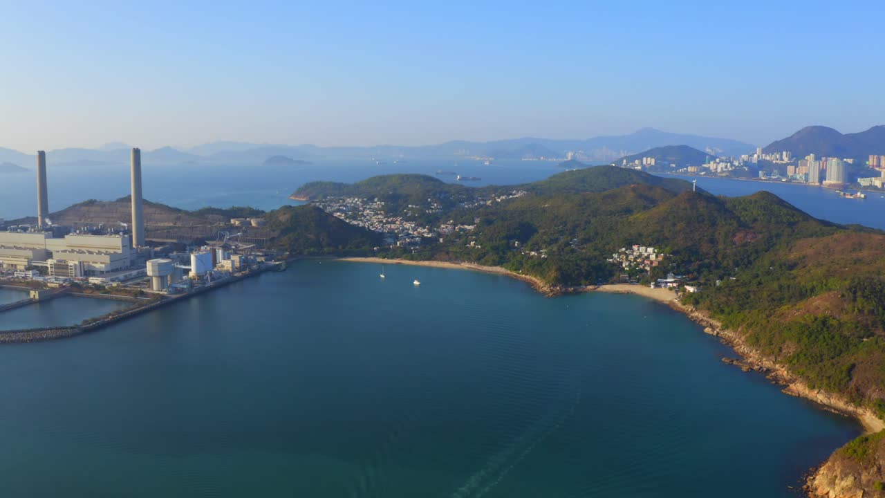 toma de drones de una gran central eléctrica costera de carbón en una isla al lado de un pueblo con una playa durante un hermoso día soleado-3