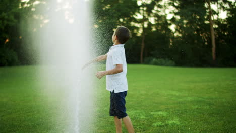 Niño-Jugando-Con-Rociadores-De-Agua-En-El-Campo