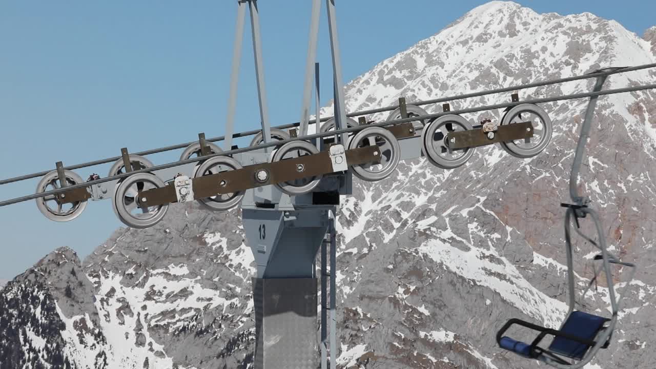 Meccanismo di funivia da sci con cabinovie che passano, con sfondo di picchi montuosi innevati