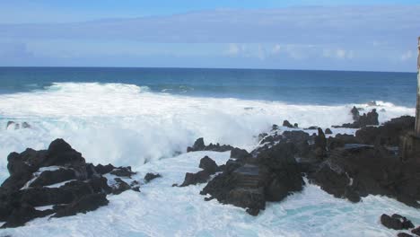 a big waves of the atlantic ocean breaks on a rocky coast on a sunny day during a storm in puerto de la cruz in the canaries , wide handheld shot