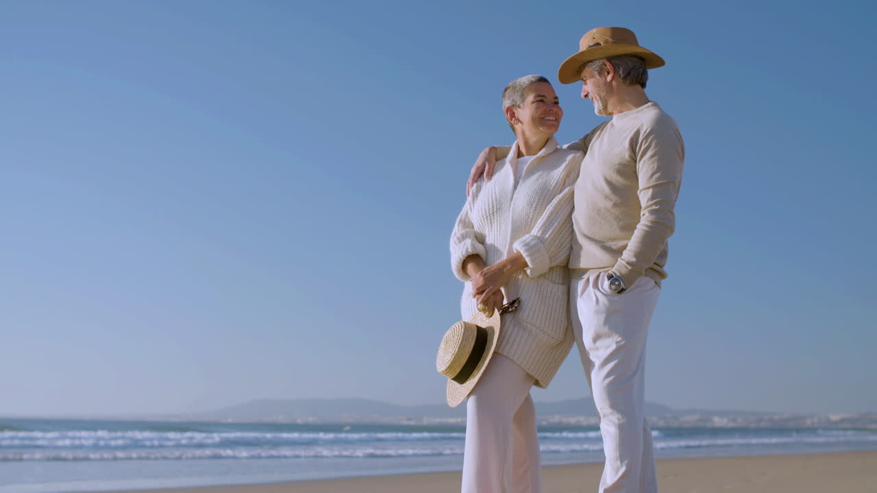 un anciano romántico abrazando a su esposa y hablando con ella en la playa