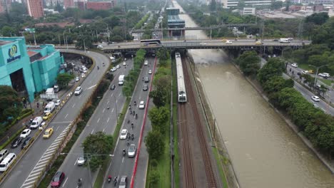 Vista-Del-Metro-De-Medellin-Saliendo-De-La-Estacion-Al-Lado-De-La-Carretera-Y-El-Rio