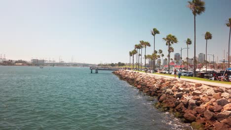 Shot-of-a-busy-marina-and-port-from-a-fishing-dock-as-people-walk-along-the-coastal-path