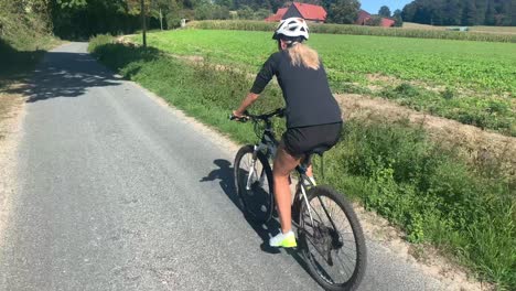 blond young girl with helmet is riding the mtb mountain bike on the road