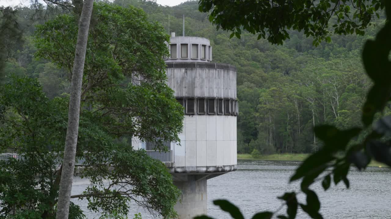 View of Clarrie Hall Dam Water Station framed by trees, showcasing the natural environment and the water facility in the distance.