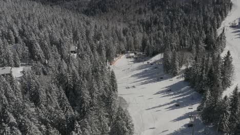 Downhill-view-with-ski-lift-at-Ribnica-track-in-Kope-winter-resort-Slovenia,-Aerial-dolly-in-shot