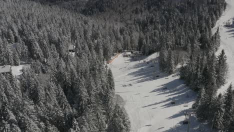 downhill view with ski lift at ribnica track in kope winter resort slovenia, aerial dolly in shot