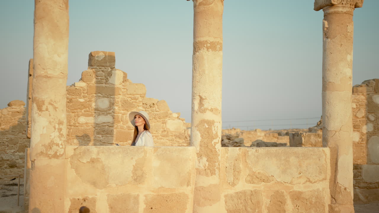 mujer explorando antiguas ruinas al atardecer