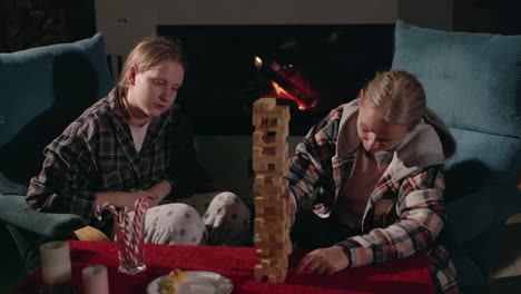 sisters playing with wooden blocks by the fireplace