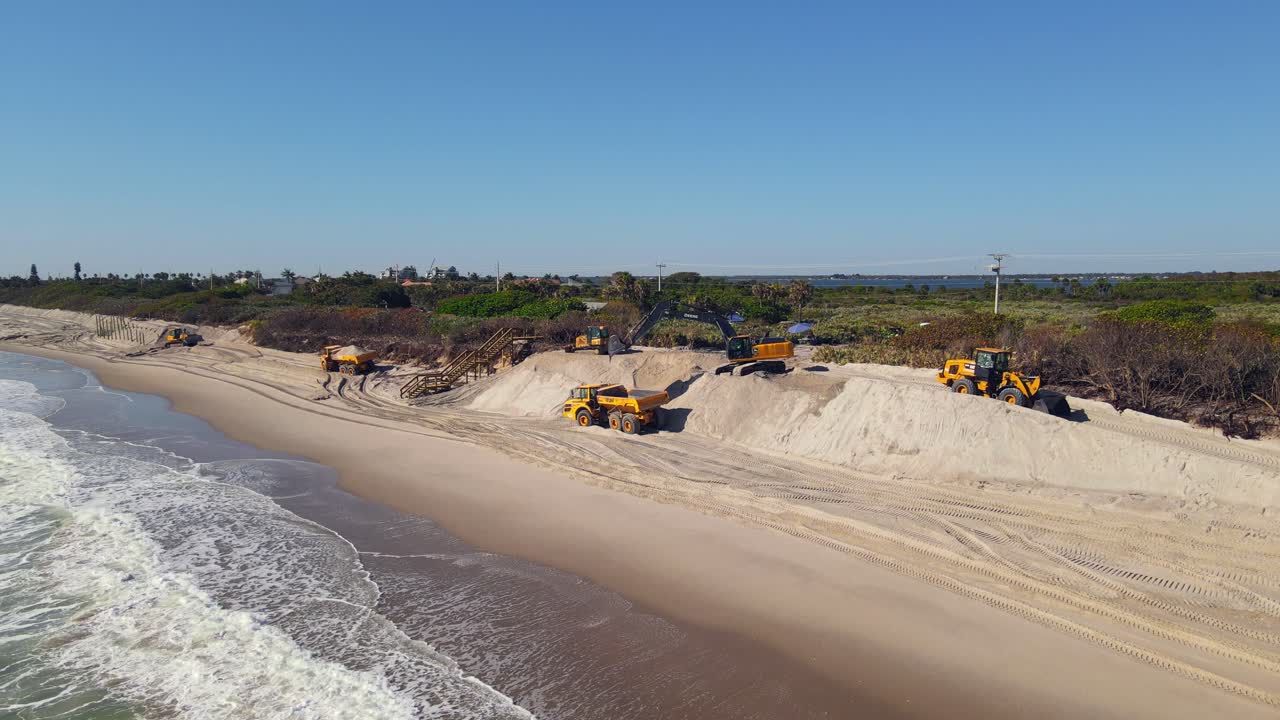 모래 를 청소 하는 뒤 에 있는 발굴기 들 과 함께 바다 물 의 공중 촬영
