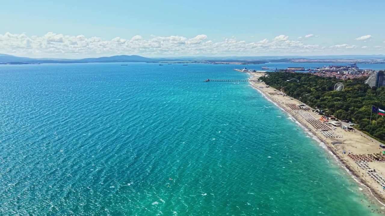 Ampia vista di una spiaggia e dell'oceano in una giornata di sole con cieli sereni e terra distante visibile sullo sfondo.