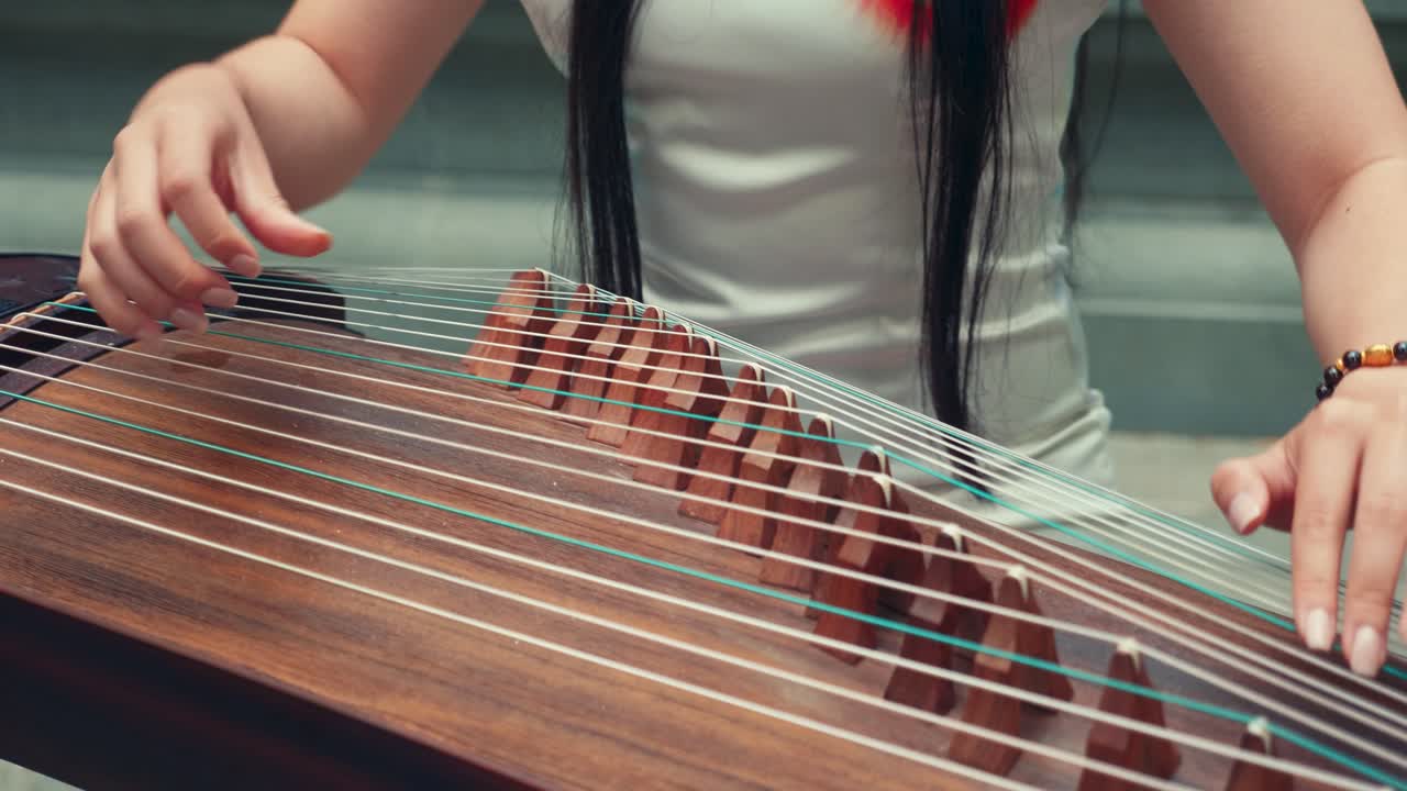 una chica china jugando al guzheng afuera.