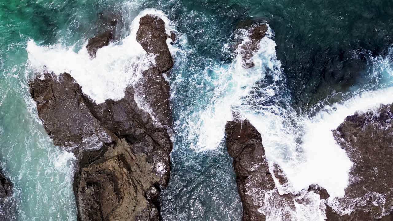 disparo aéreo de arriba hacia abajo de las olas que se estrellan contra una roca en la playa