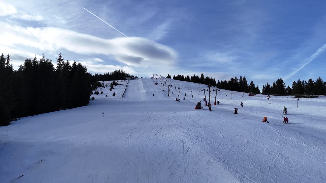 Riprese con drone che sorvolano una pista da sci in una soleggiata giornata invernale. Paesaggio invernale alpino.